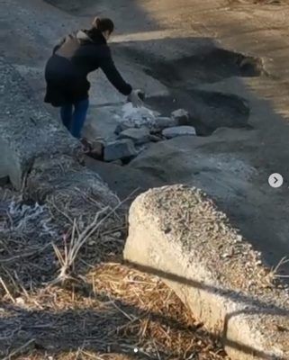 Девушка закидывает яму камнями